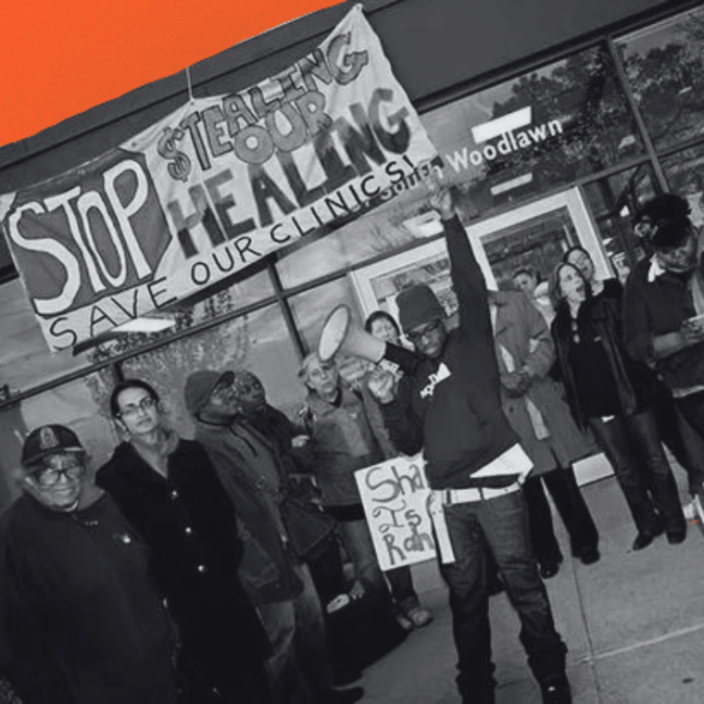 A group of protestors stands outside a building, with one person in front holding a megaphone. A large banner above them reads "STOP STEALING OUR HEALING. SAVE OUR CLINICS."