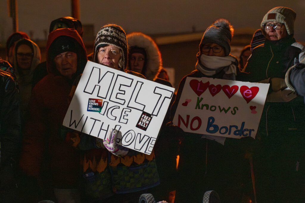 A person in a crowd holding a sign that says, "Melt ICE with Love."